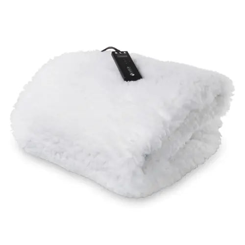 A white fleece massage table warmer pad laid flat under a fitted sheet on a professional spa bed, showing an attached digital temperature controller.